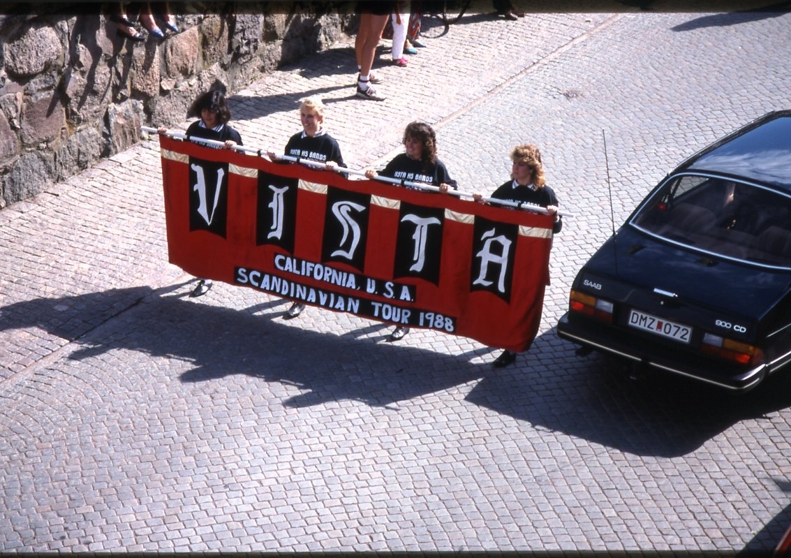 Bild uppifrån mot Brahegatan med tre ungdomar som bär en banderoll med texten "Vista California U.S.A Scandinavian Tour 1988", efter följer musikkåren Vista High School Band.