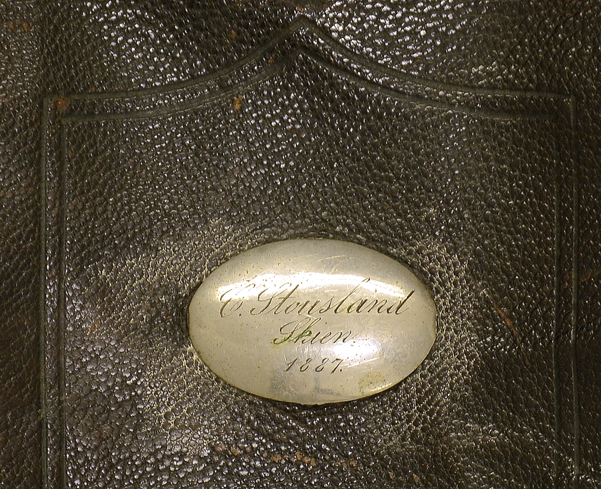Veske. Fra protokollen: Skulderveske av skinn, svart m. lås og utanpålomme m. namneskilt: C Stousland, Skien, 1887.