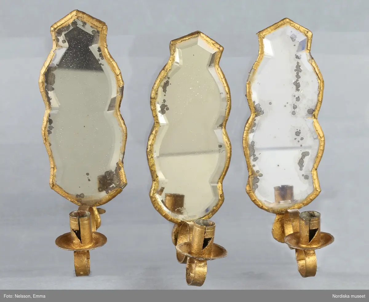 Inventering Sesam 1996-1999:
H 10,5 cm
12 st spegellampetter, konturerat spegelglas med facettslipning, bakstycke av furu. Ljusarm av ihoprullat stålband. Några glas med fläckar.
Tillhör dockskåp 151.825.
Birgitta Martinius 1996