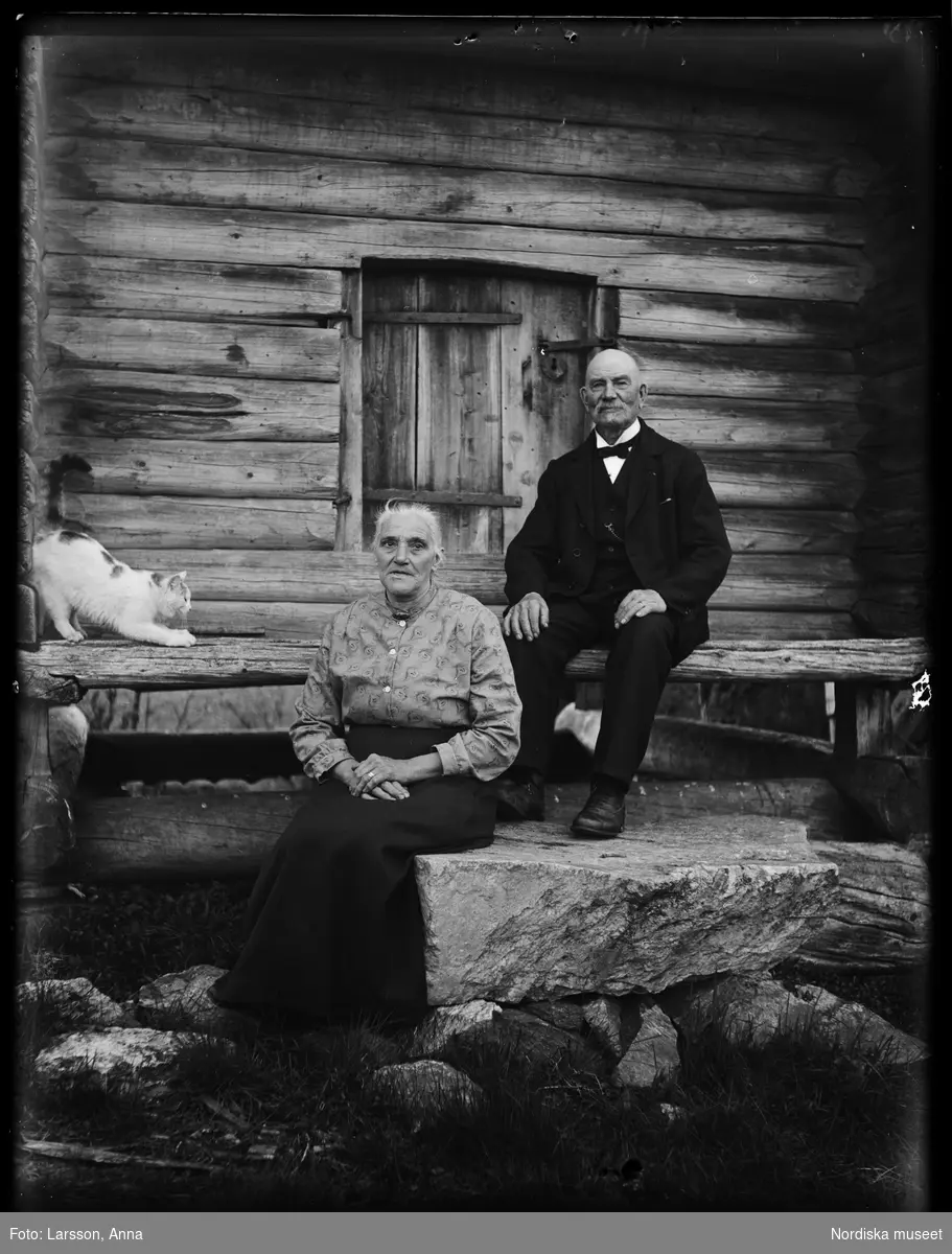 Lantbrevbäraren Erik Stolpe (1854-1956) i Heden med hustrun Klara (1866-1956), sittande framför härbre. 