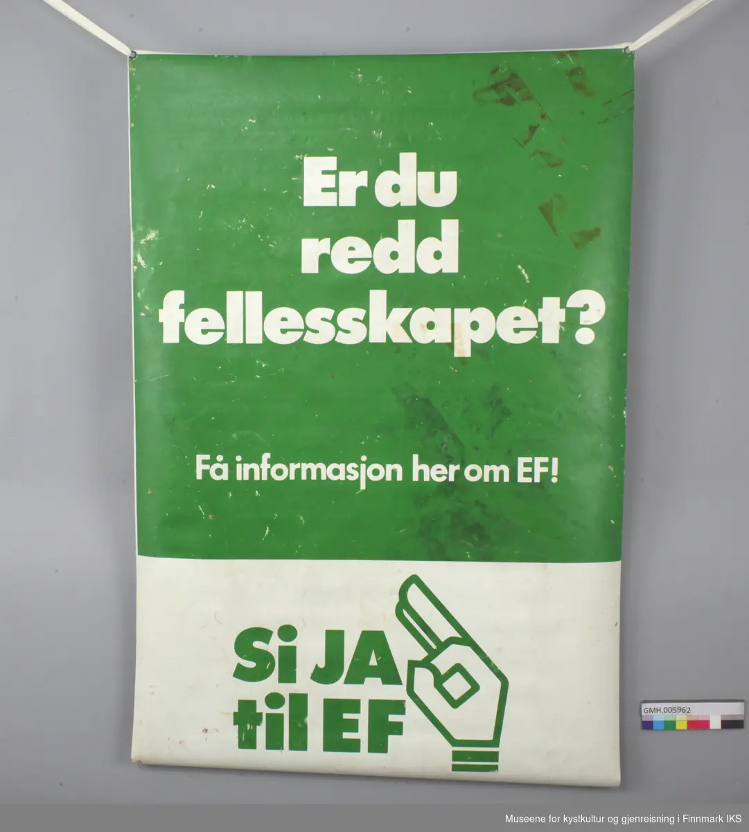 Banner er laget av kunststoff med en malje av metall i hvert hjørne. En av maljene mangler. På den ene siden står det i grønn og hvit «Er du redd fellesskapet? Få informasjon om EF! Si ja til EF». På den andre siden står det rødt på hvitt «Slå vakt om Norges framtid». 