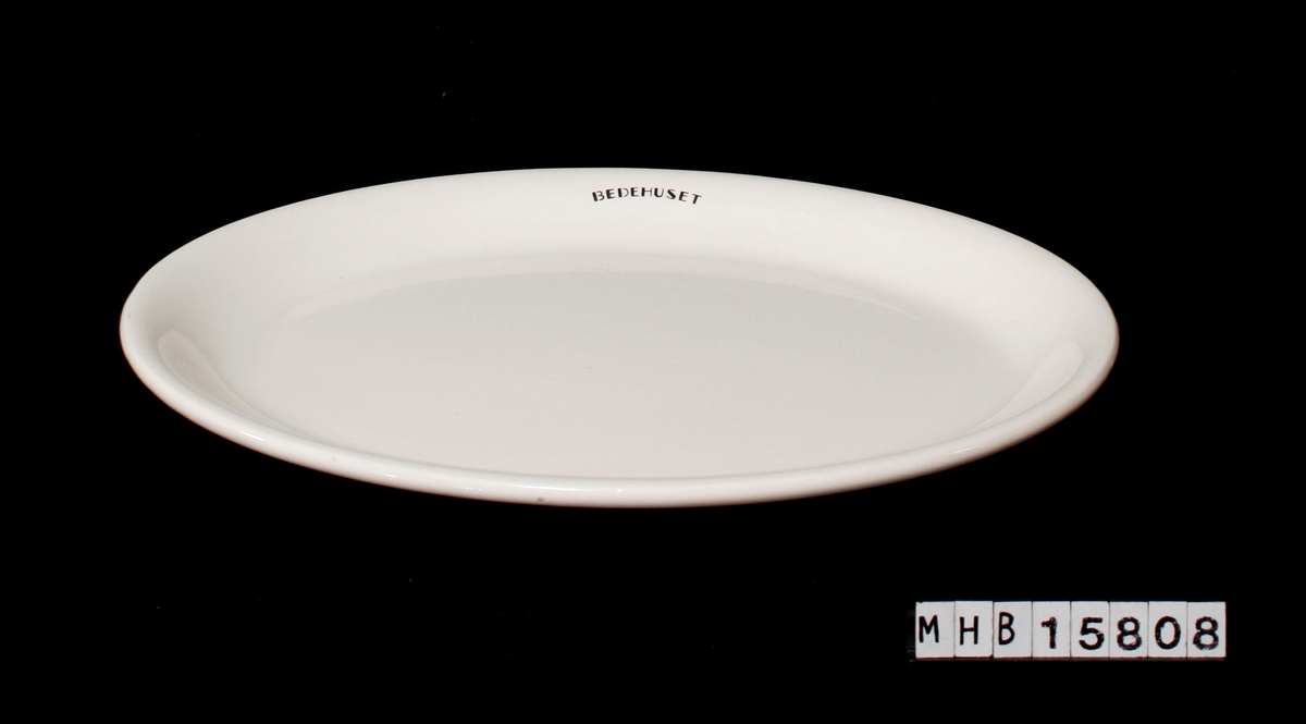 Et ovalformet fat, med påskrift Bedehuset. Hvit glasert keramikk.