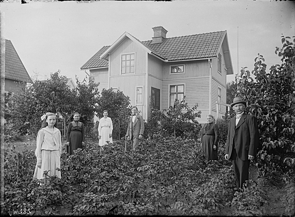 Fotografering beställd av Johansson. Föreställer sannolikt vagnlyftaren Johan Axel Johansson (1867-1952) till höger, samt hans hustru Ida Lovisa Lindevall (1871-1951) som nummer två från vänster och deras barn Fritz Axel (f. 1899), Edit Lovisa (1901-1960) och Ellen Teresia (1904-1994). Den äldre kvinnan är ej identifierad. Här bosatta på Granelund 9 (stg 2262) i Västerås.