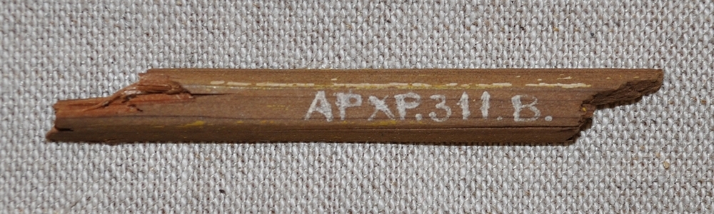 10 fragment av kavaj i brunt ylletyg som tillhört Fraenkels kavaj. I en av fickorna fanns en liten del av en blyertspenna.