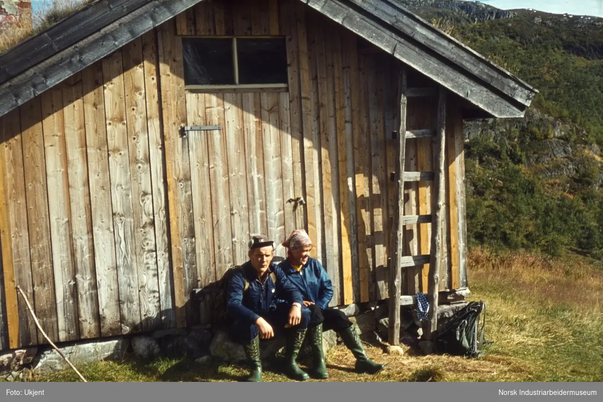 Anne og Bjørn Dyrland sitter inntil husvegg i Åmotsdal