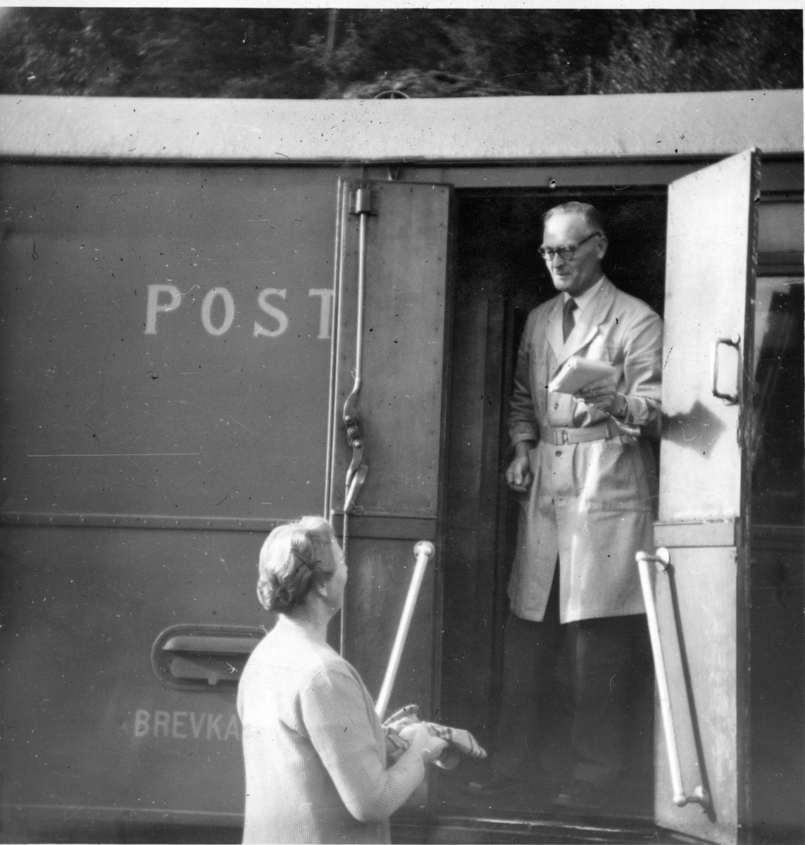 Ekspeditør Gunnhild Aurebekk får eller leverer post til betjent ombord på Setesdalsbanen mens toget står på Røyknes stasjon. 