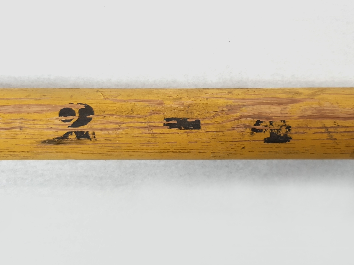 Båtshake, bestående av en stång i trä målad med gula och röda ränder. Samt med en s-formad krok av metall i ena änden. Märkt vid sidan "2 - 4" med svarta bokstäver.