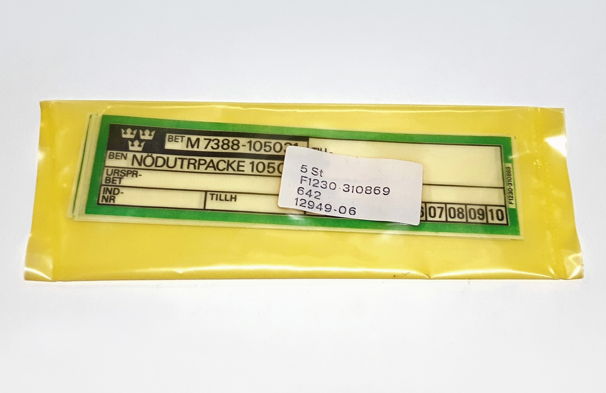Skylt av textil, 5 stycken, till Nödutrustningspacke 105C, K. Vardera skylt är försedd med benämning och M-nummer. Samtliga är förpackade i en etikett-försedd påse av plast.
