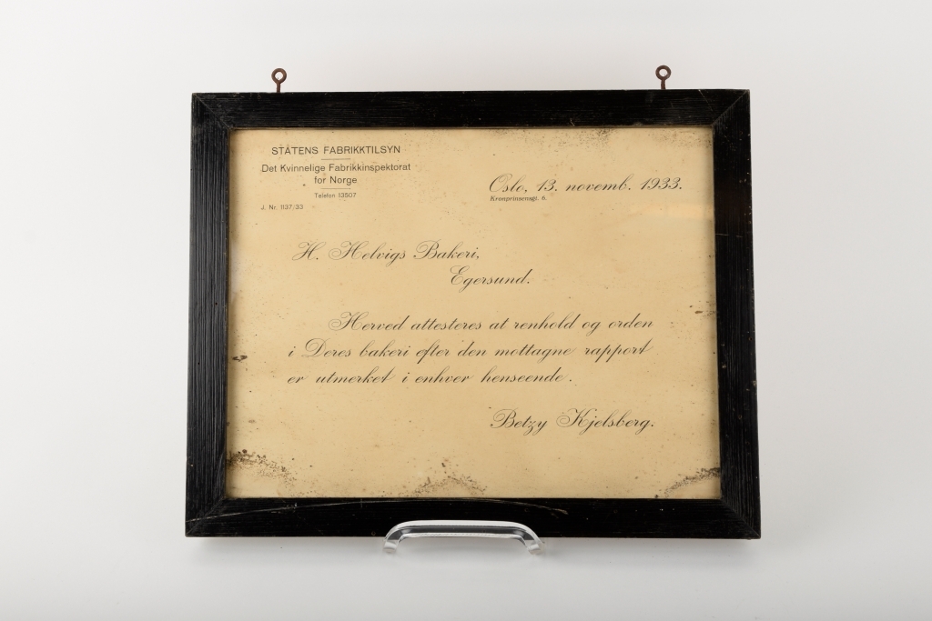 Et innrammet sertifikat utstedt til Helvigs Bakeri vedrørende godkjente renholds- og ordensforhold.
