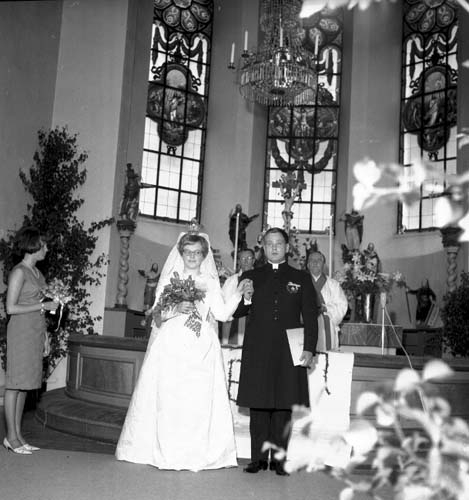Ett brudpar står vid ett altare vända mot besökarna.