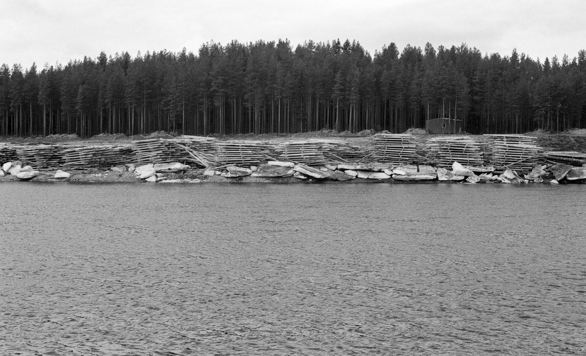 Valbyvelta ved elva Flisa i Åsnes i Solør, fotografert våren 1964. Fotografiet er tatt fra motsatt side av vassdraget, som her er vidt og stilleflytende. Vinteren 1964 var kald og snøfattig i denne delen av landet. Følgelig ble det tjukk i på alle vassdrag. Dermed var det stor fare for sein isløsning og isgang i elvene. Det gikk imidlertid bedre enn fryktet. Da dette fotografiet ble tatt lå det fortsatt en del grove isflak i elveskråningen framfor velteplassen. Bakenfor lå det strøvelter med fløtingstømmer, som etter hvert skulle slås på elva for fløting til nedenforliggende skogindustri. I strøveltene lå tømmeret i floer, parallelt med vassdraget, og med mellomliggende strøstokker, som skulle sikre god lufting. Luftinga var viktig, for den bidro til at virket fikk en forsiktig tørk før det ble slått på vannet for fløting videre. Etter en snøfattig vinter ble tømmerveltene i 1964 tidlig bare, og de fikk en god tørk. Dermed ble det lite søkketømmer dette året. Fløtinga dette året startet i slutten av april, og sluttrensken passerte Flisa i midten av juli.