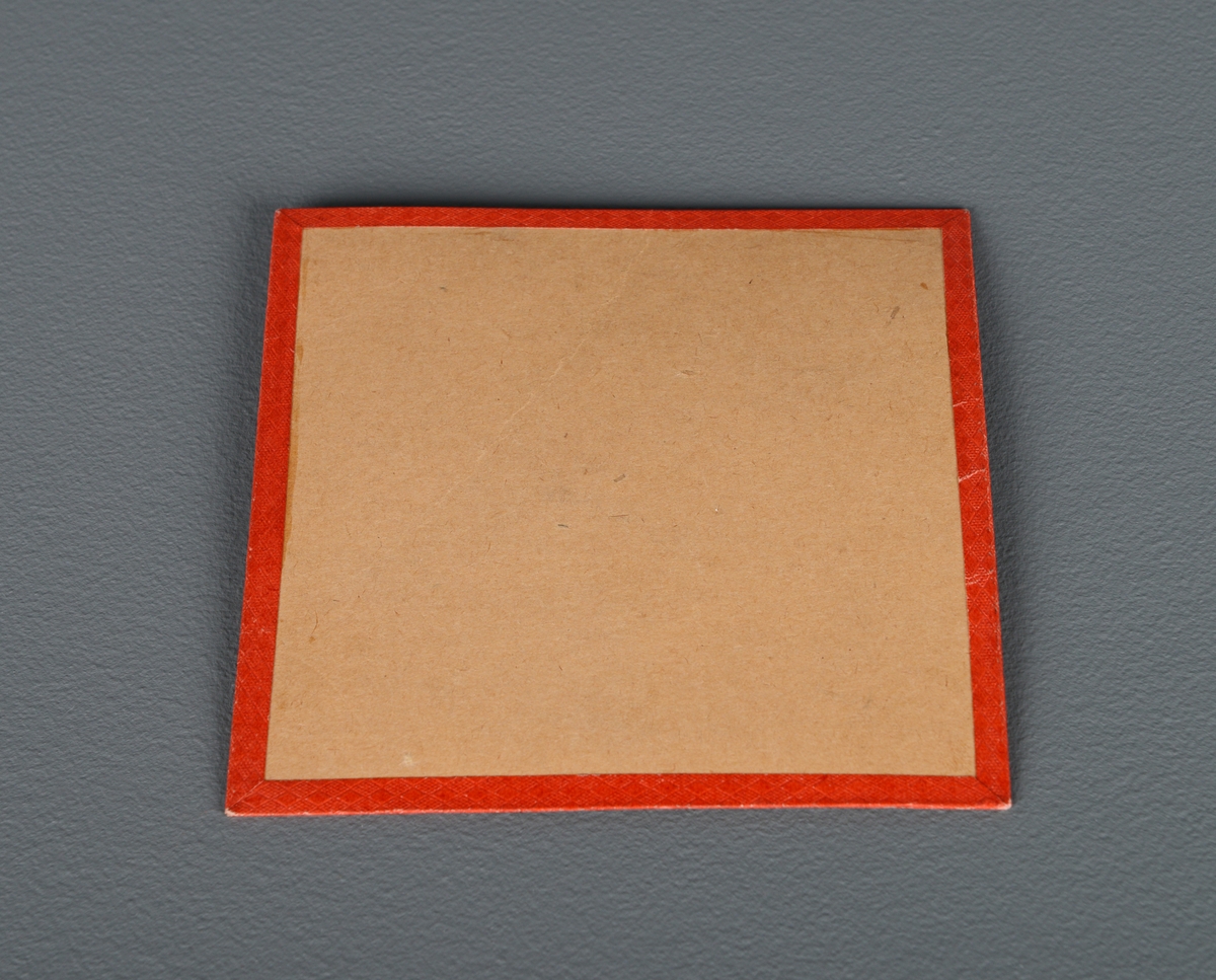 En kvadratisk plate med pålimt gangetabell fra 1 til 10. Det er en rød kant rundt. Platen er llitt bøyd slik at papiret på fremsiden har en tynn rift på skrått ned fra midten.