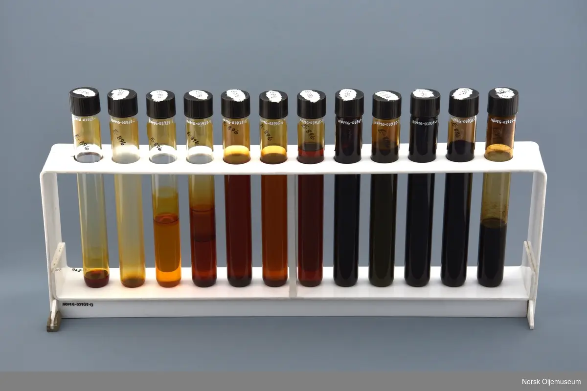 Stativ med tolv oljeprøver i reagensrør. 

Oljeprøvene er eksempler på forskjellige oljekvaliteter fra lett- til tungolje produsert ved Vallø Oljeraffineri.