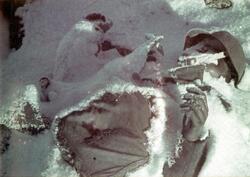 Død soldat ligger delvis dekket av snø.