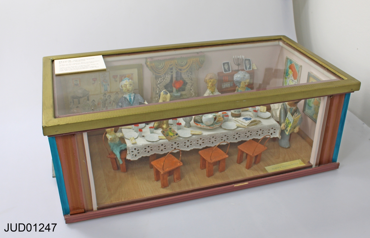 Pesachscen med dockor i glasmonter, betitlad "Sedermåltid i hemmet".