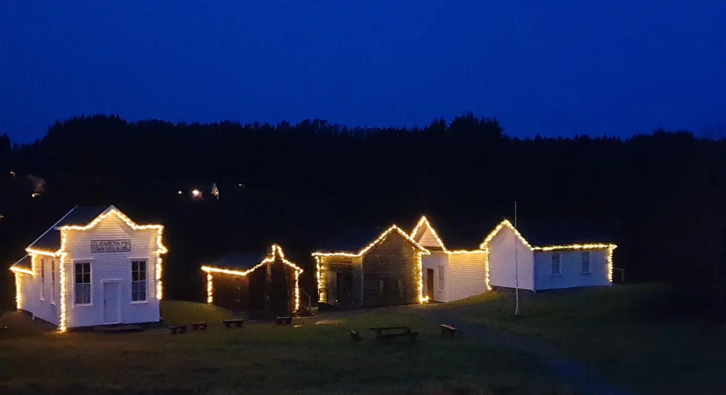 Vinterlys i førjulstid. Prærielandsbyen lyser i silhouette under blå og mørk kveldshimmel