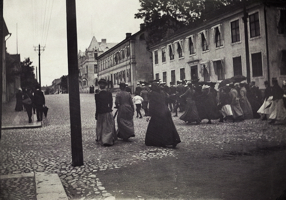 Studentdagar i Växjö, ca 1910.
Studenter på marsch längs Kronobergsgatan norrut, tätt följda av nyfikna. Till höger ser man husen i kvarteren Kristina och Lejonet med apotekshuset, Kronobergsgatan 6.