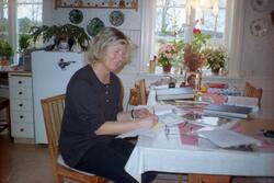 En kvinna sitter vid köksbordet i Sunnanåker med papper, pen