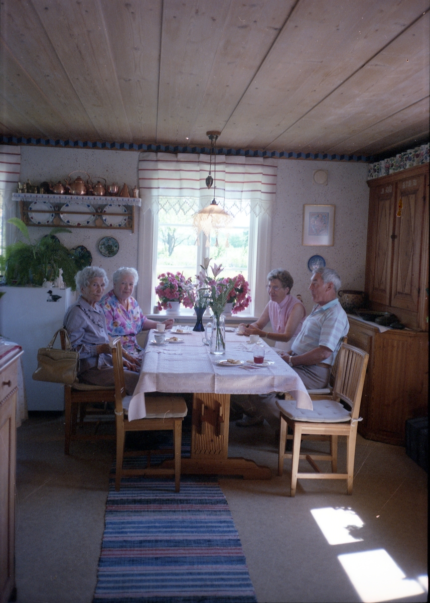 Tre kvinnor och en man sitter vid dukat kaffebord i köket i Sunnanåker.