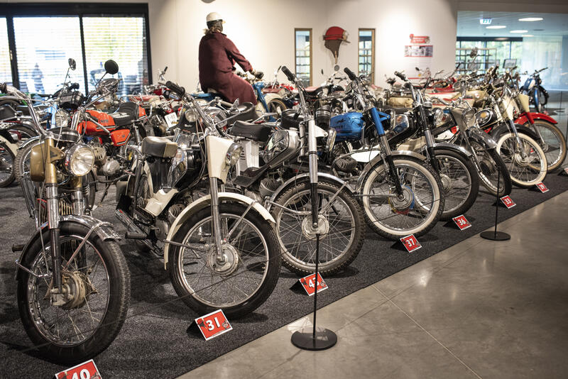 Overiktsbilde av utstillingen Pottehjelm og totakt. Mange mopeder fra 1900-tallet ved siden av hverandre.