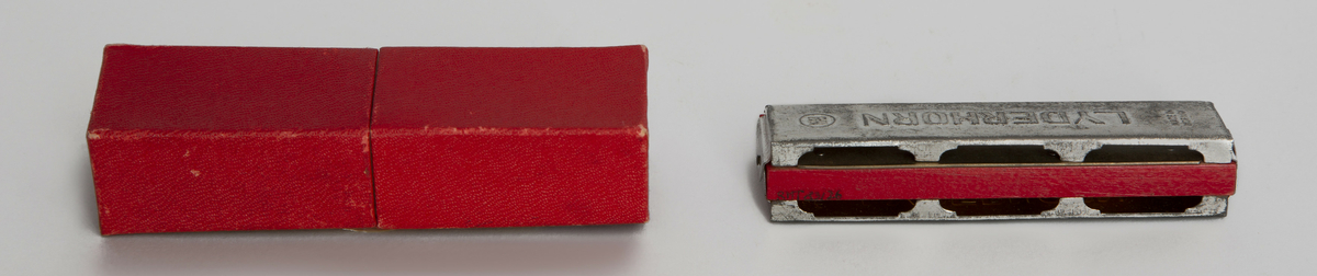 Tremolomunnspill i metall og rødmalt tre med 20 metalltunger. Medfølgende eske av kartong.
