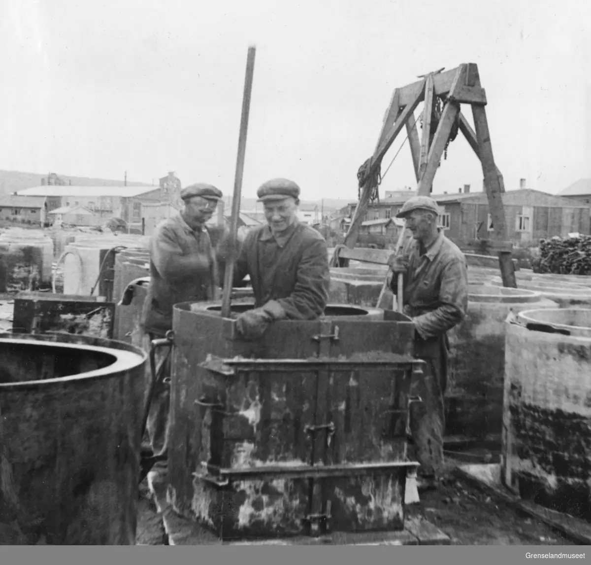 Støping av kloakkrør i forbindelse med byggingen av velferdshus, Kirkenes 15. juli1948. Dampsentralen i bakgrunnen.