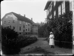 En kvinne ved lærerskolen på en sti foran en bygning på høyr
