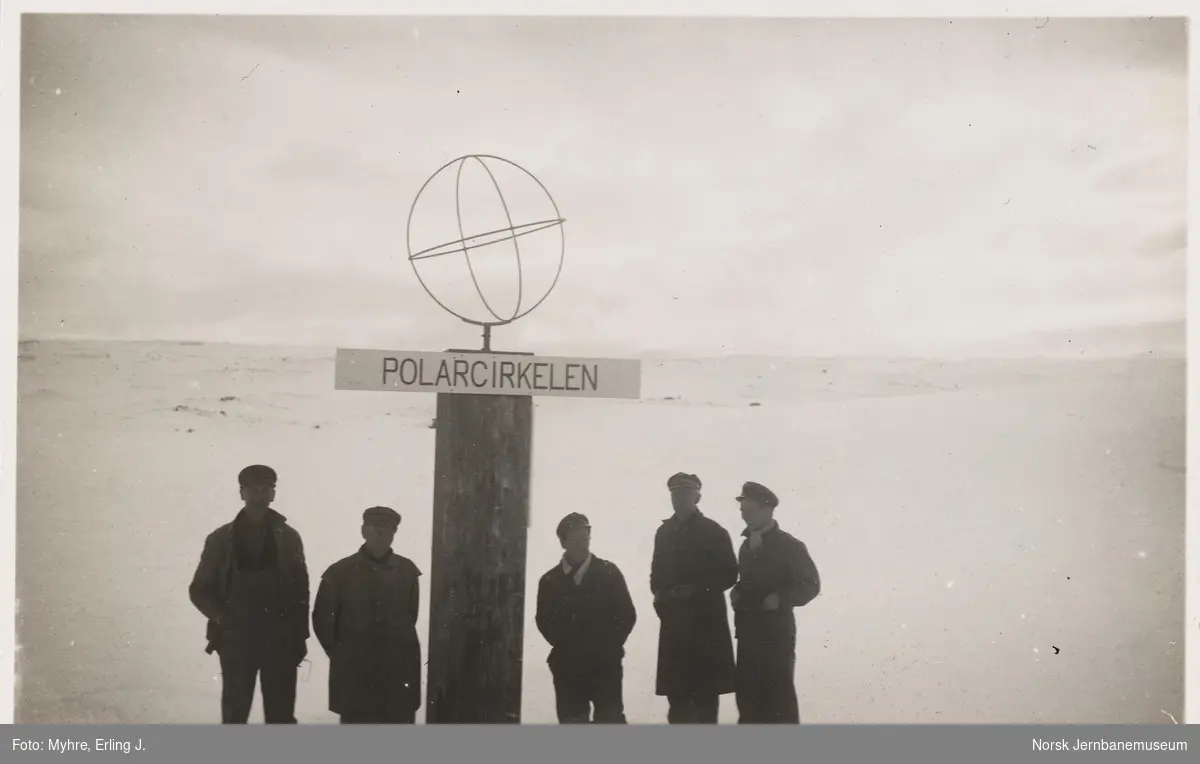 Lokomotivpersonale på snøryddingstog ved monumentet ved Polarsirkelen