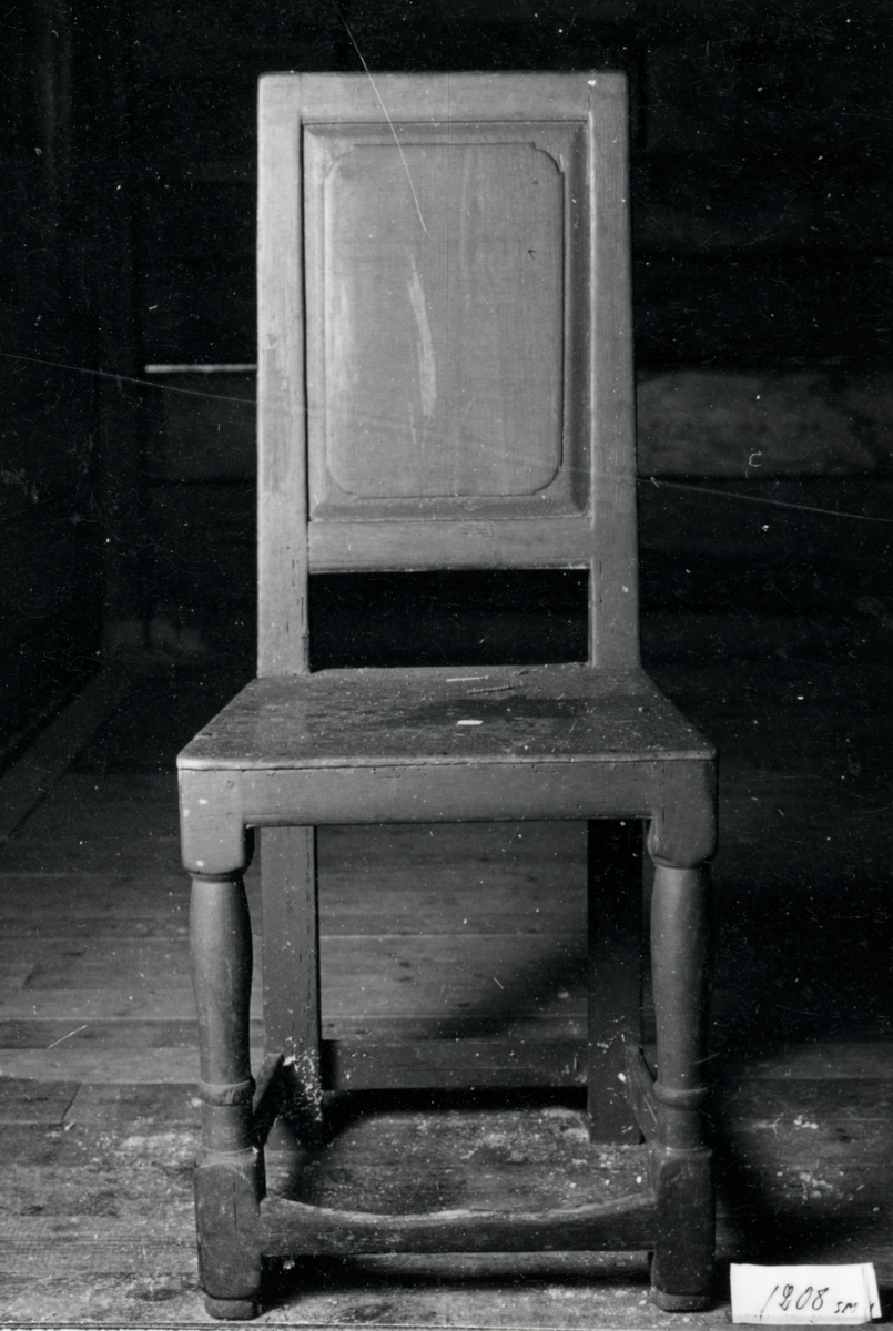 Brunmålad stol med hel rygg, svarvade framben 4- sidiga bakben, lågt sittande tvärslåar, träsits.