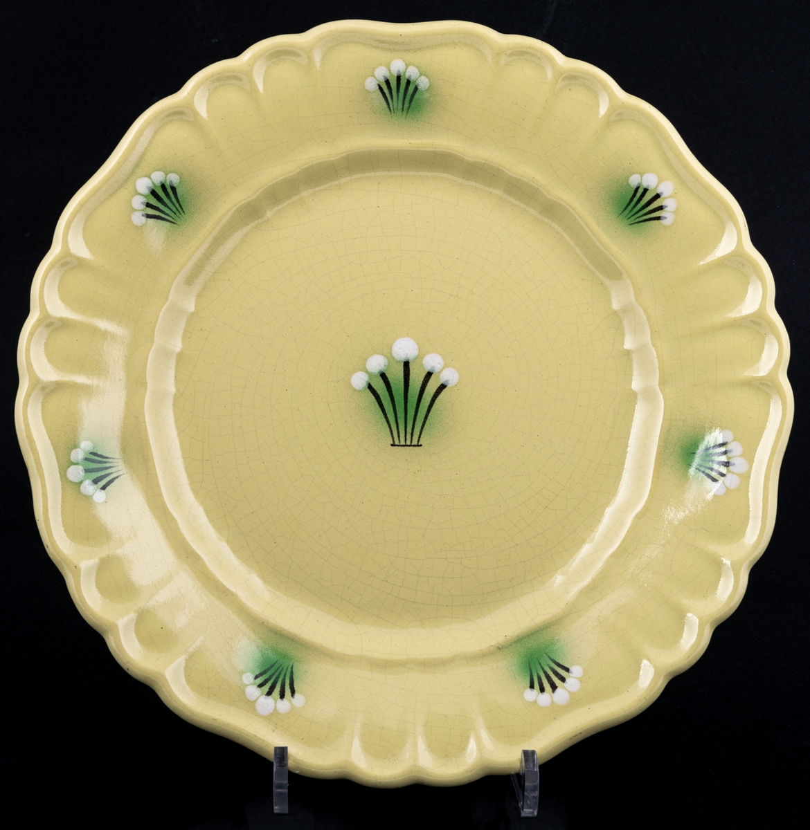 Mattallrik ur bordsservisen och dekoren Orient, tillverkad 1930-33, modell S. Dekoren Orient har gul glasyr med handmålade knippen i brunt, grönt och vitt på brämen samt i spegeln.