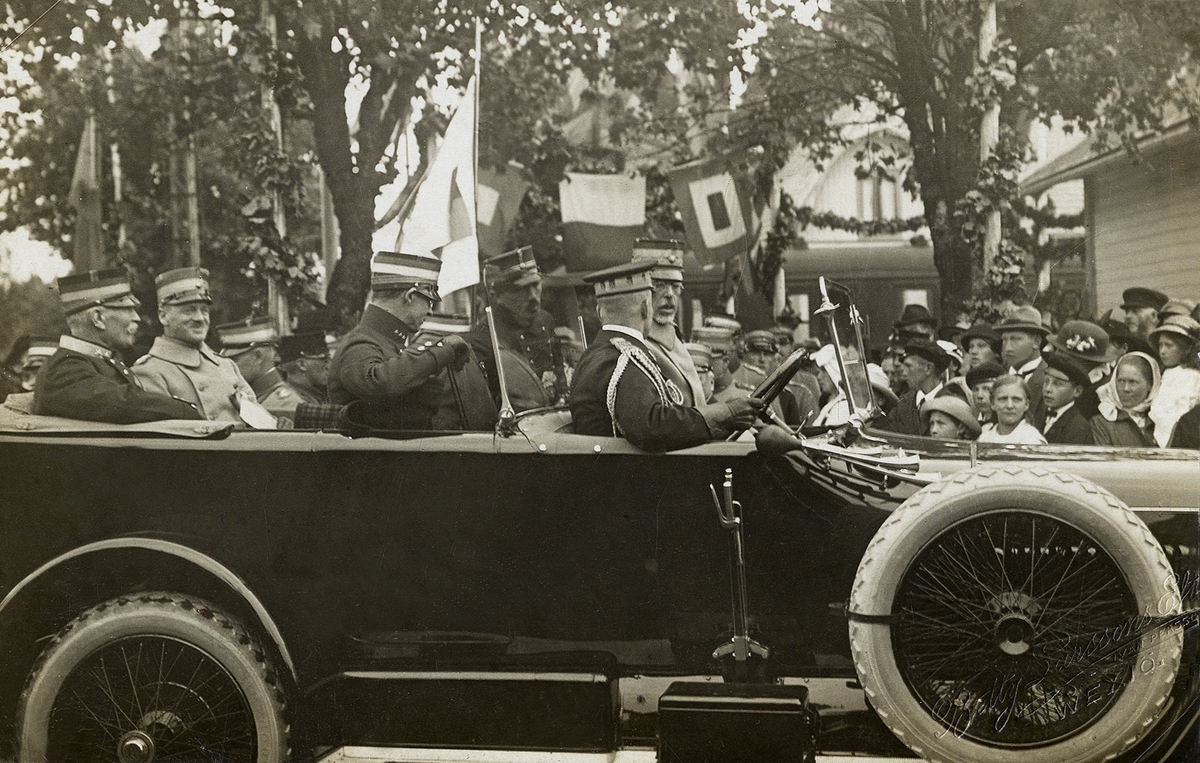 Gustaf V i bil, på besök i Växjö 1917, i samband med en militärmanöver. Fotot är trol. taget på stationsplanen framför järnvägsstationen.
