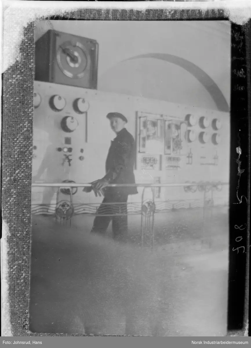 Mann som står foran en styring- og/eller måleinstrumentkonsoll.