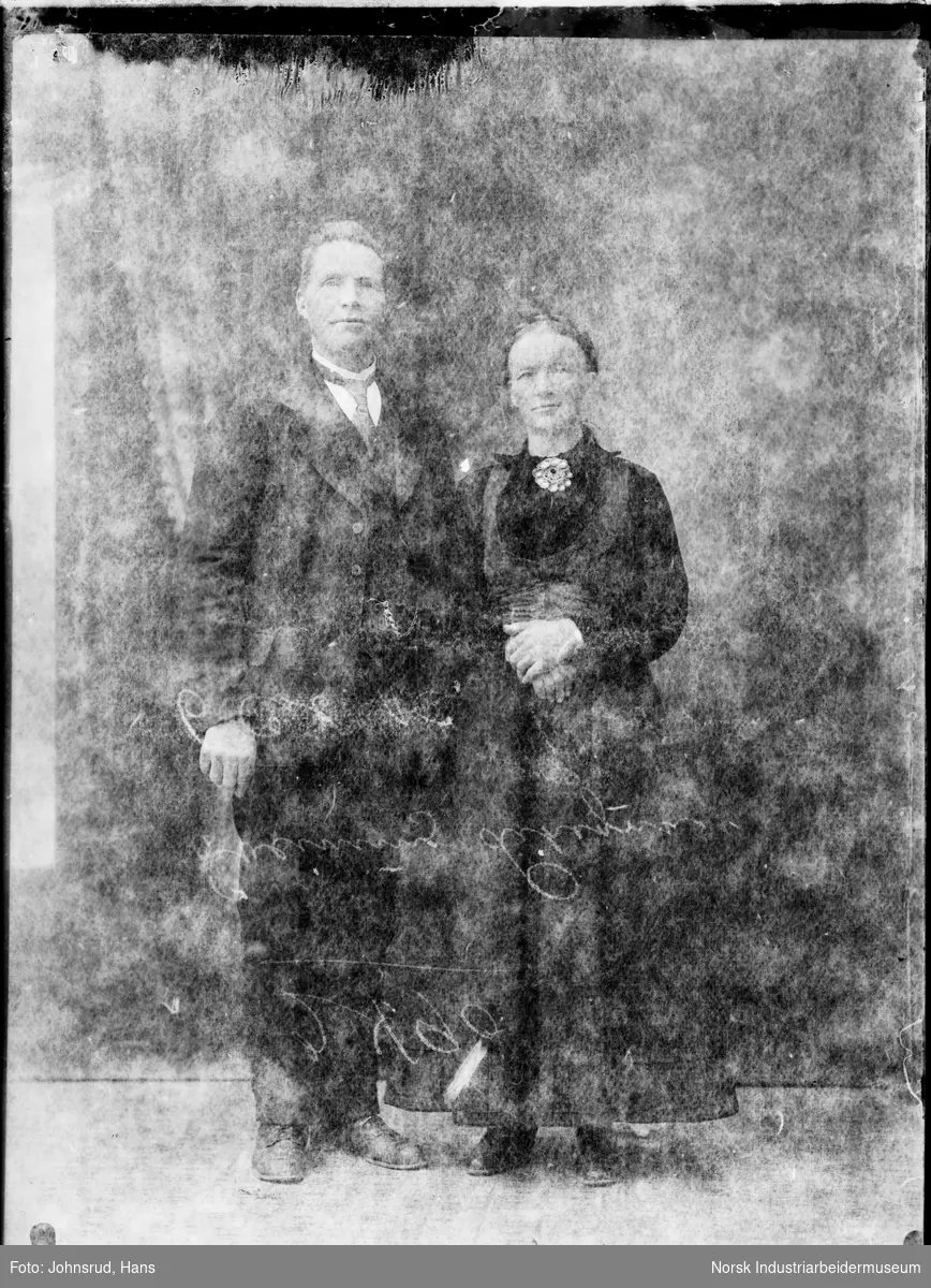 Portrett av stående mann i dress og kvinne i bunad.