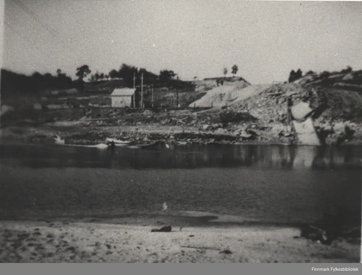 Rester etter hengebrua over Karasjokka (Karasjohka), 1947. Vi ser elva og på andre siden ser vi et hus.