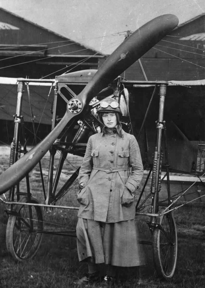 Porträttfoto av Elsa Andersson, Sveriges första kvinnliga flygförare, framför flygplan Thulin A på flygskolan i Ljungbyhed, 1920.