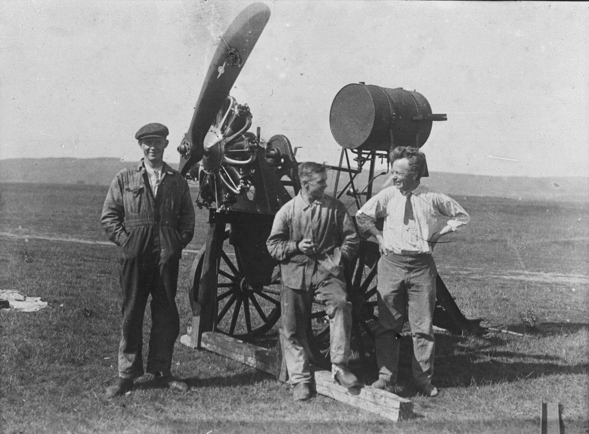 En mobil provbock för Thulin-motorer står på ett fält, 1910-tal. Tre män står bredvid.