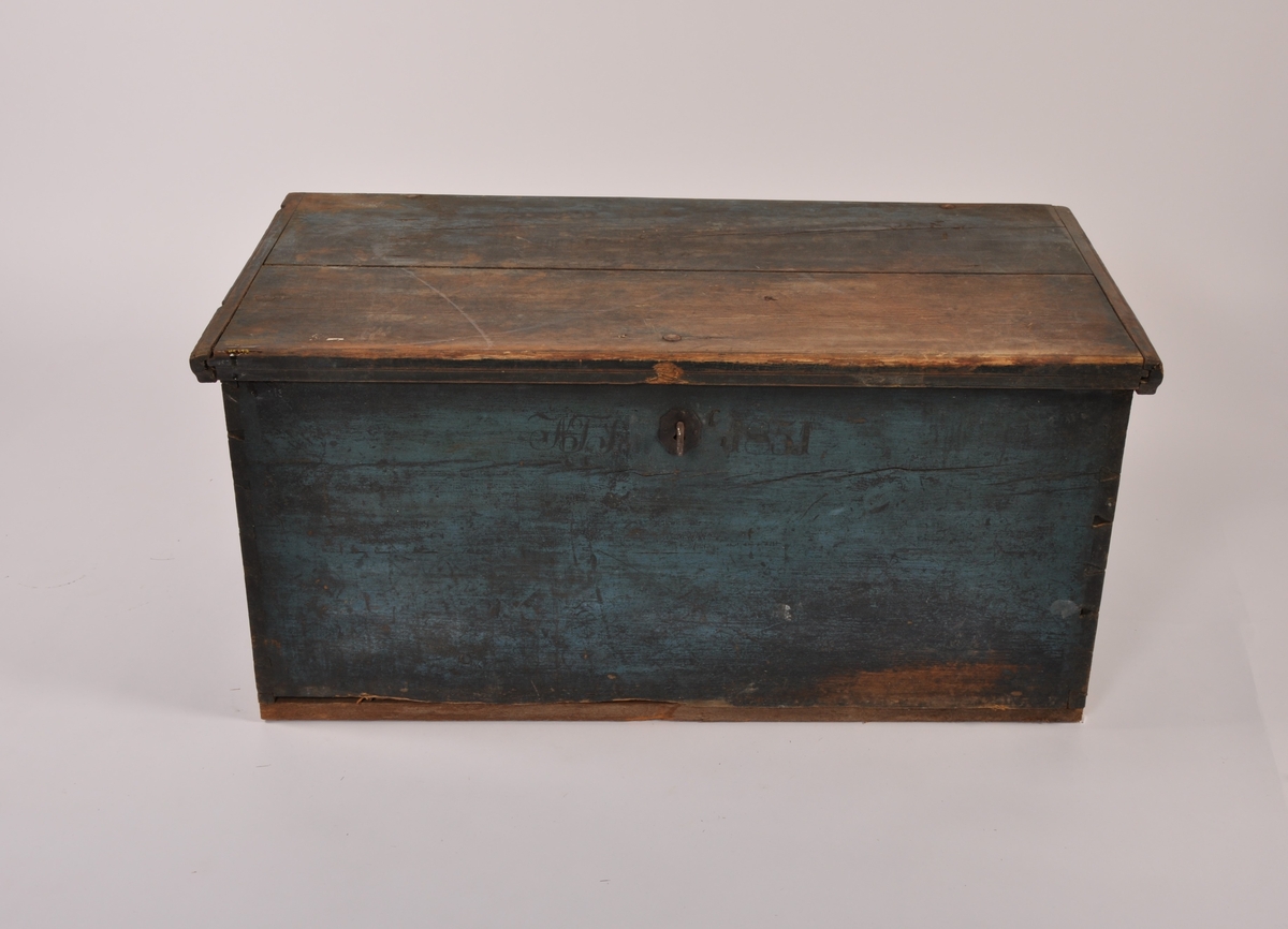Kiste i tre med flatt lokk med profilerte lister, 2 jernhåndtak. Blåmalt, med rødmalt bakside. Med leddik. Med lås og nøkkel.