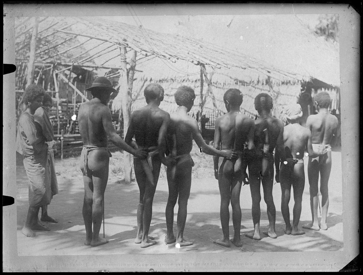 Bilden visar en grupp män från ursprungsbefolkningen bakifrån i Manila.