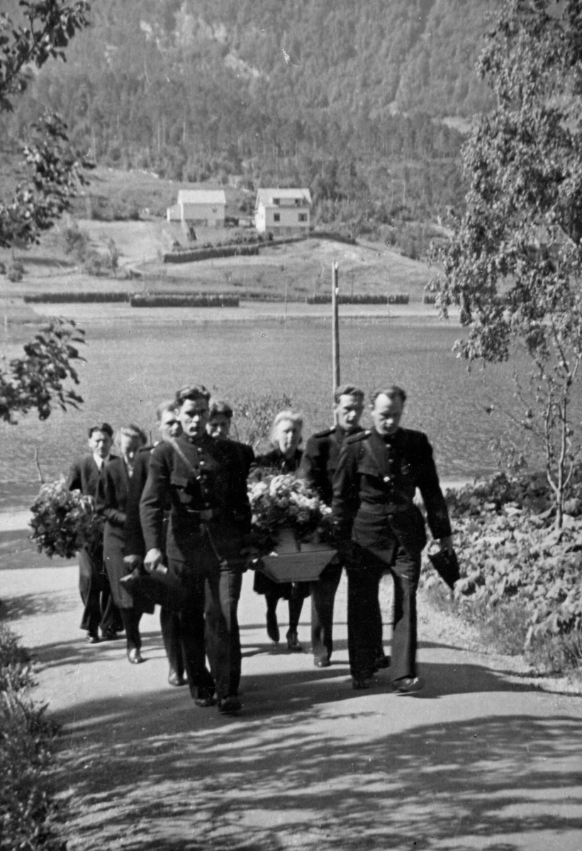 Fire politimenn i uniform bærer ei barnekiste. To menn og to kvinner fylgjer etter båra.