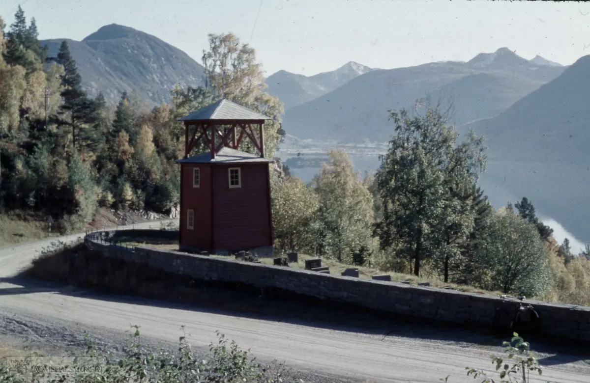 Tjelle gravplass. Gravplassen vart oppretta i 1957 og tatt i bruk same året. Klokkehuset bygd av Olaf K. Gussiås. .Vistdalen ses i bakgrunnen.
