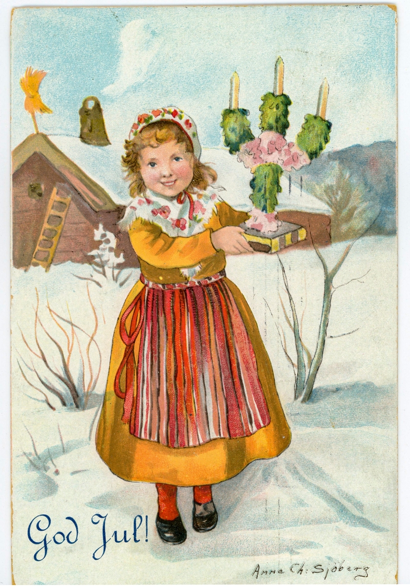 Julkort med motiv av flicka i folkdräkt hållandes en trearmad ljusstake. Flickan står ute i snön på tomten till en gård. Till vänster om flickan står texten: " God Jul!". 

Bilden är målad av Anne Charlotte Sjöberg (1864- 1947), som var en känd , svensk tecknare och grafiker. På baksidan finns ett grönt 5- öres frimärke med Kung Gustaf V. Vykortet är poststämplat men det går inte att datera det då stämpeln är otydlig.