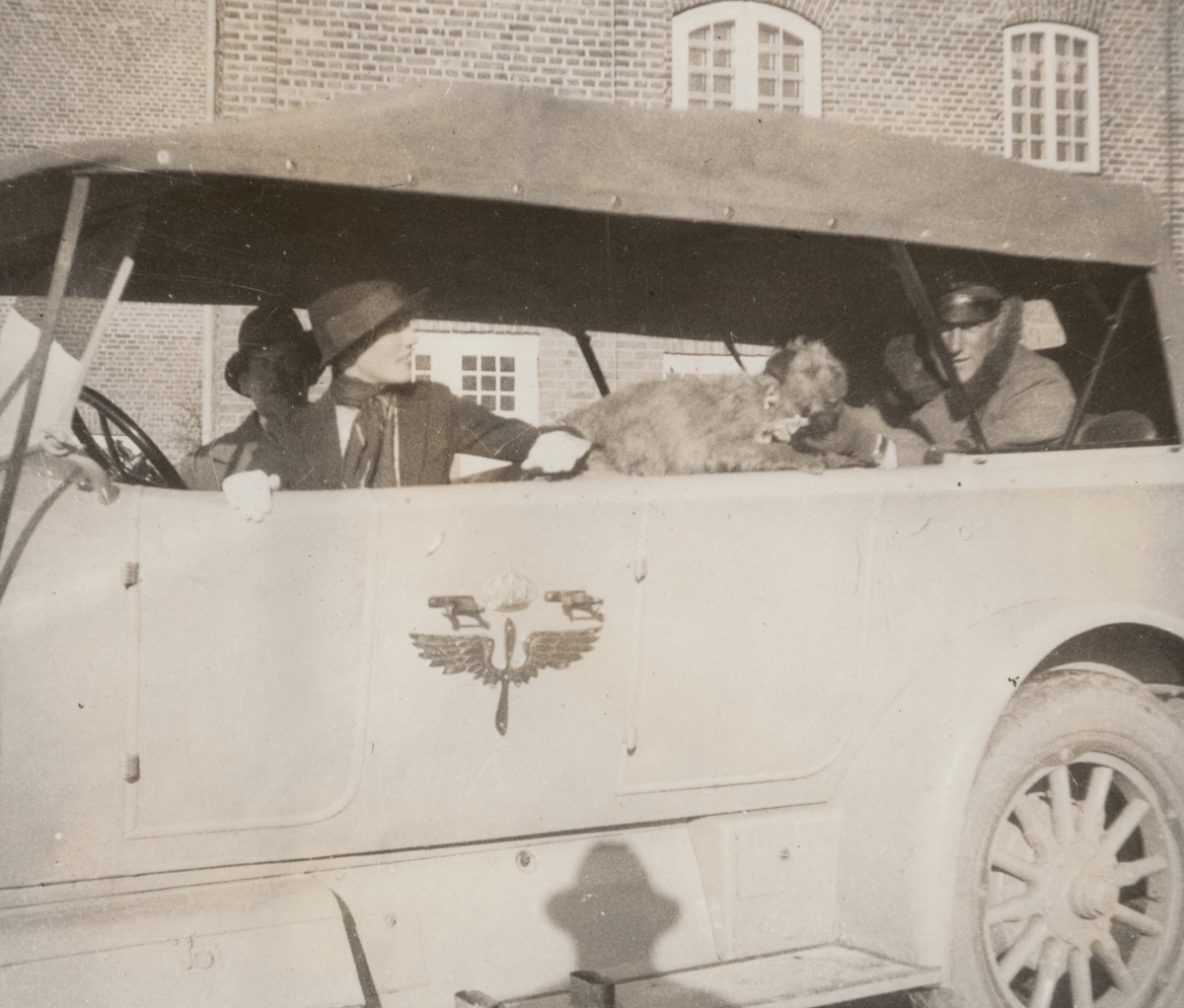 Tre personer och en hund sitter i Flygkompaniets bil, cirka 1925. Mannen till vänster är militären Birger Schyberg, mannen till höger är militären Nils Kindberg. Kvinnan heter Anna Linderstam.

Text i album: "Jan. 1925. Strängnäs. Qvisse. AL. BK. P-löv."