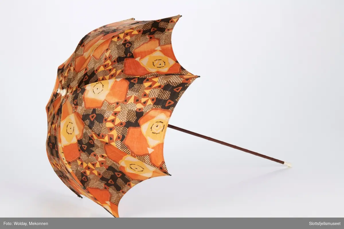 Liten parasoll med 8 spiler, trukket med bomullstekstil. Lang skaft med tupp og ende i bein. 