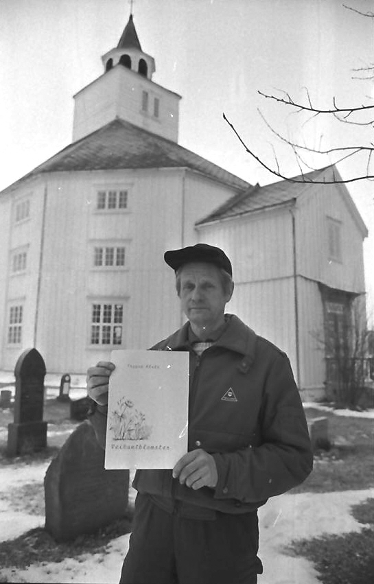 Jarle Tolgensbakk foran Tolga kirke med bok i hånda. 