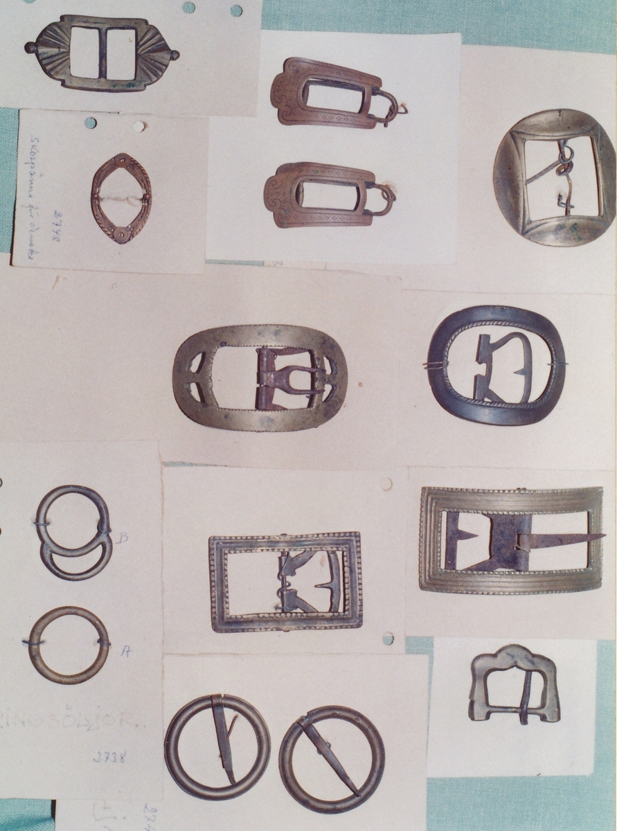 Spännen av mässing i olika modeller, skospännen, knäspännen, ringsöljor m.m. monterade på pappskiva.
  
Birgitta Blixt 2021.