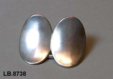 Todela halsspenne sett saman av to ovale, konkave plater, halde saman av ring. 