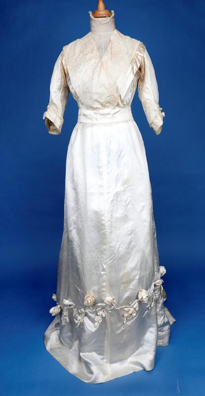 Todelt brudekjole med belte, bukettholder, hansker, slør og myrtekrans formet som hjerte. Kjolen er fra Sør-Odal. Ca 1900.