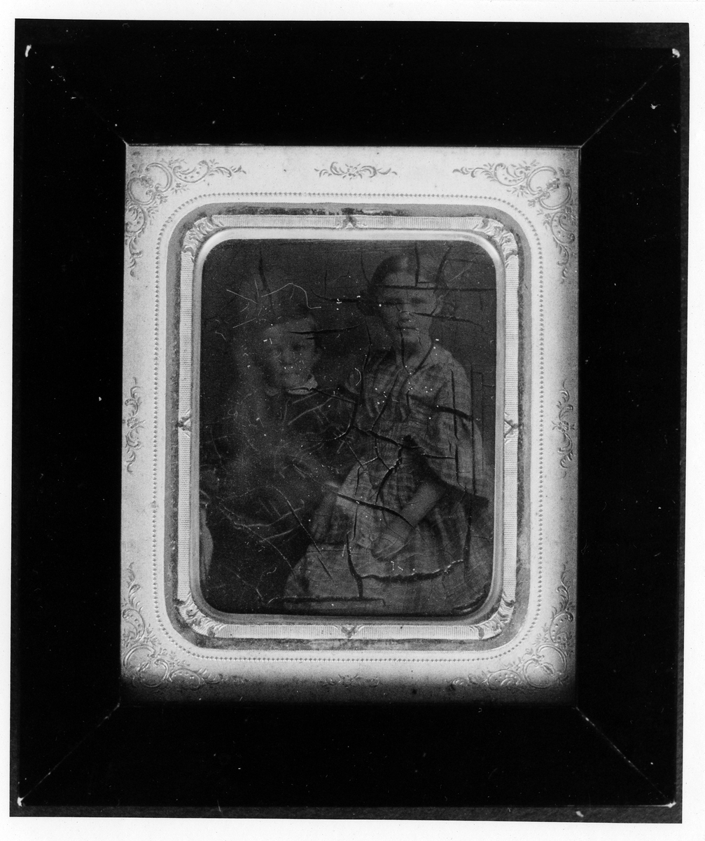 Porträtt, panotypi i rektangulär form med rundade hörn. Bilden visar två barn, en flicka, i rutig klänning, med en yngre pojke bredvid sig.