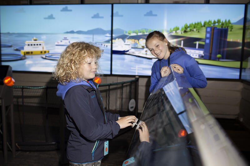 To barn koser seg i den virtuelle sjømatbyen FinCity på Norges Fiskerimuseum