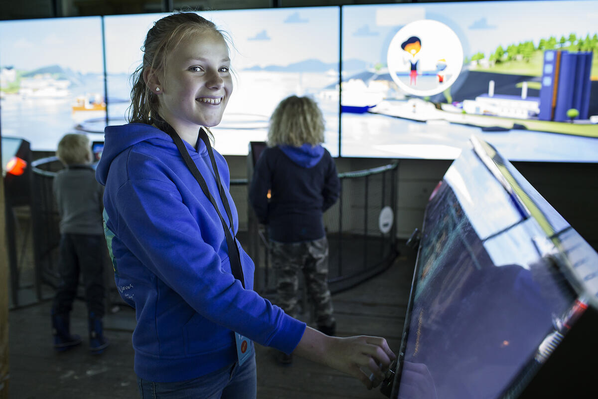 En glad jente spiller i den virtuelle sjømatbyen FinCity som du kan prøve om du kommer til Norges Fiskerimuseum